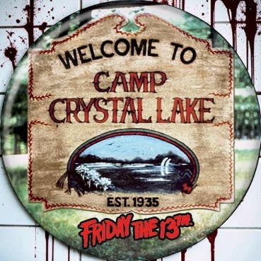 Halloween-Emporium Friday the 13th Camp Crystal Lake button featuring a rustic sign design on a blood-splattered wall.