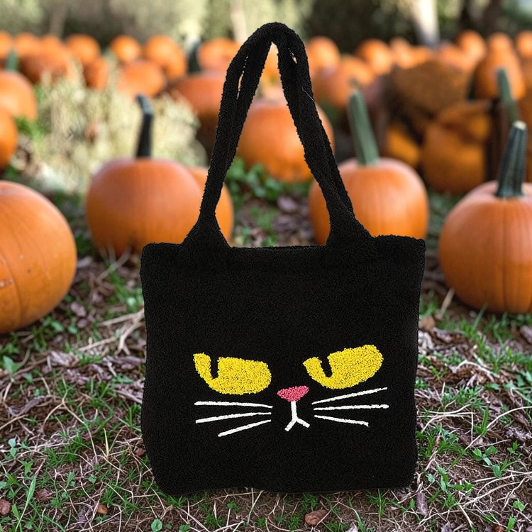 Halloween-Emporium black furry tote bag featuring an annoyed cat face with yellow eyes in a pumpkin patch.