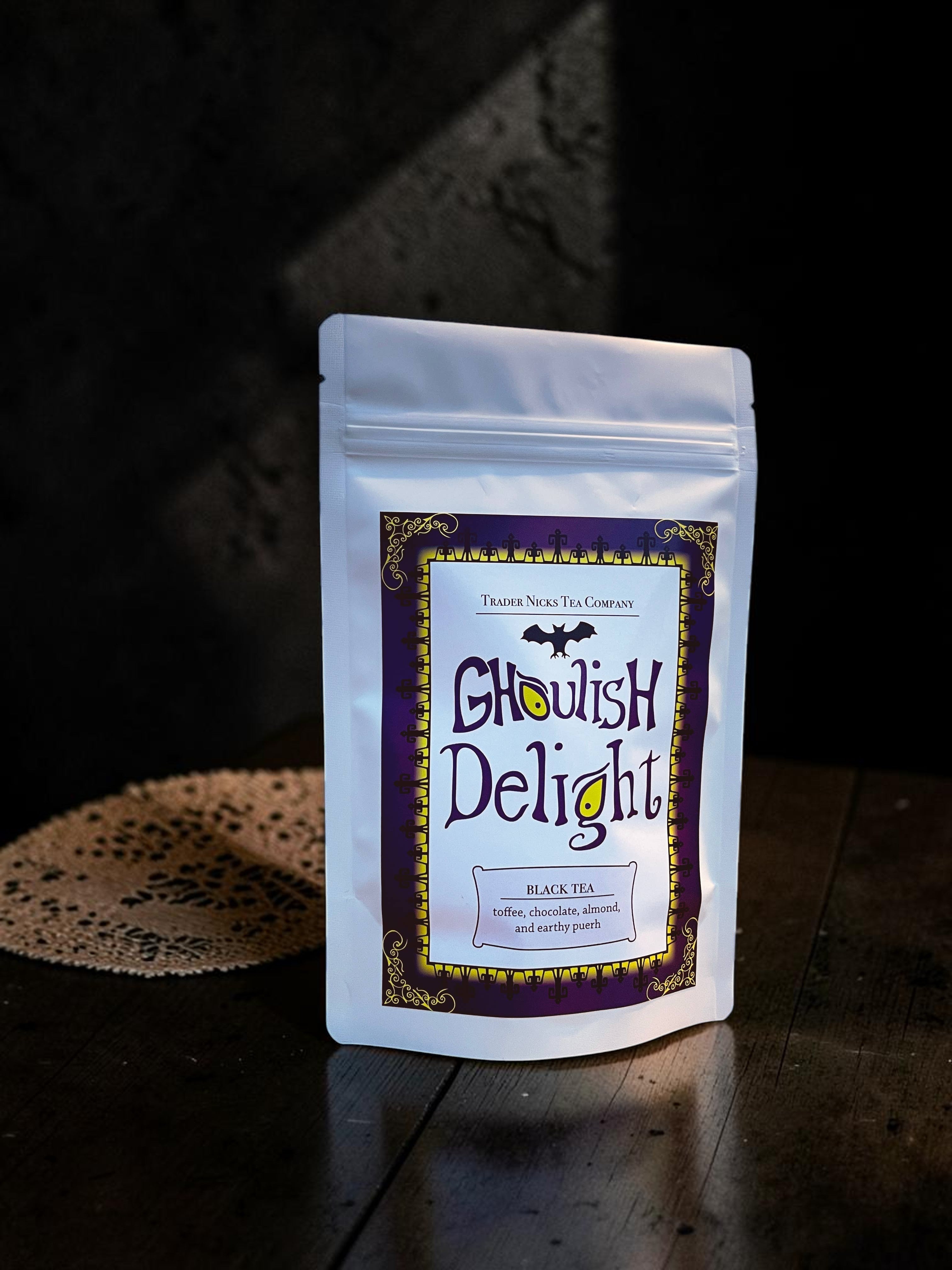 Halloween-Emporium Ghoulish Delight black tea in a white stand-up pouch with a spooky purple and gold bat label.