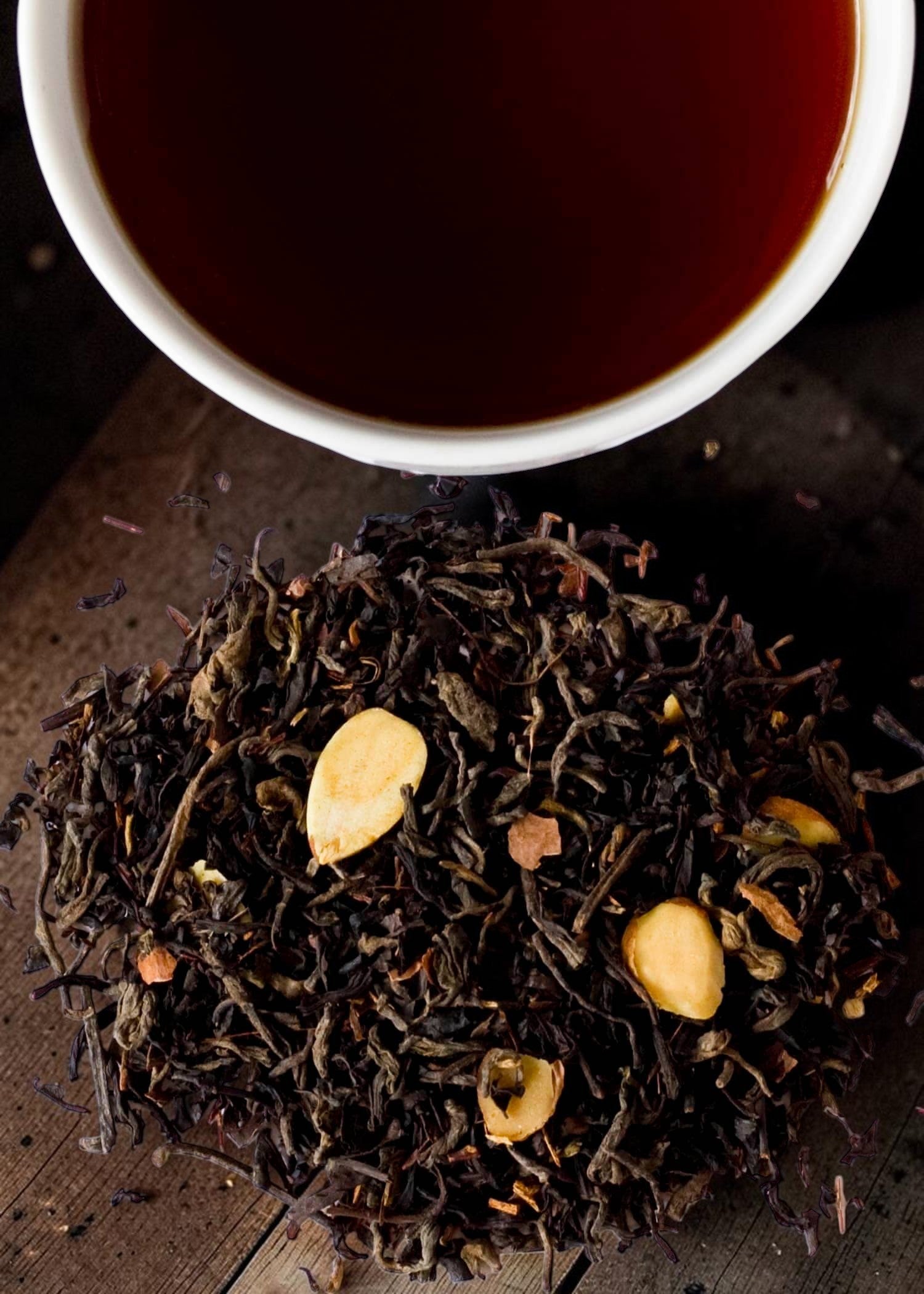 Halloween-Emporium Ghoulish Delight chocolate black tea blend with almond slices and puerh leaves next to a cup of tea