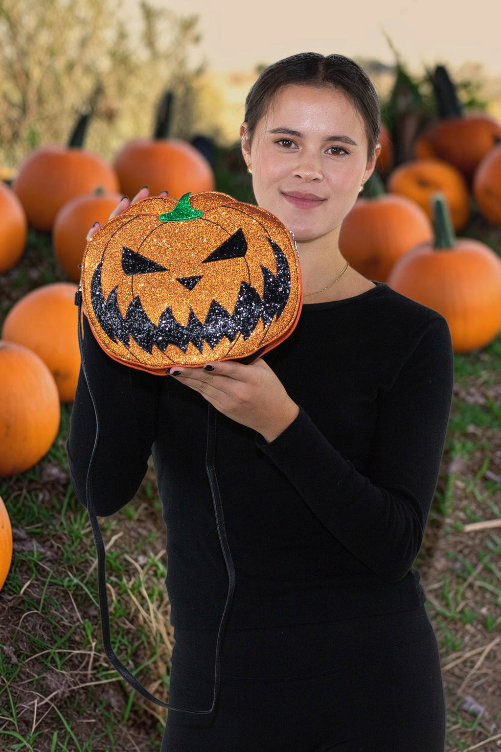 Halloween-Emporium glitter jack-o-lantern crossbody bag with orange vinyl and black smile in a pumpkin patch