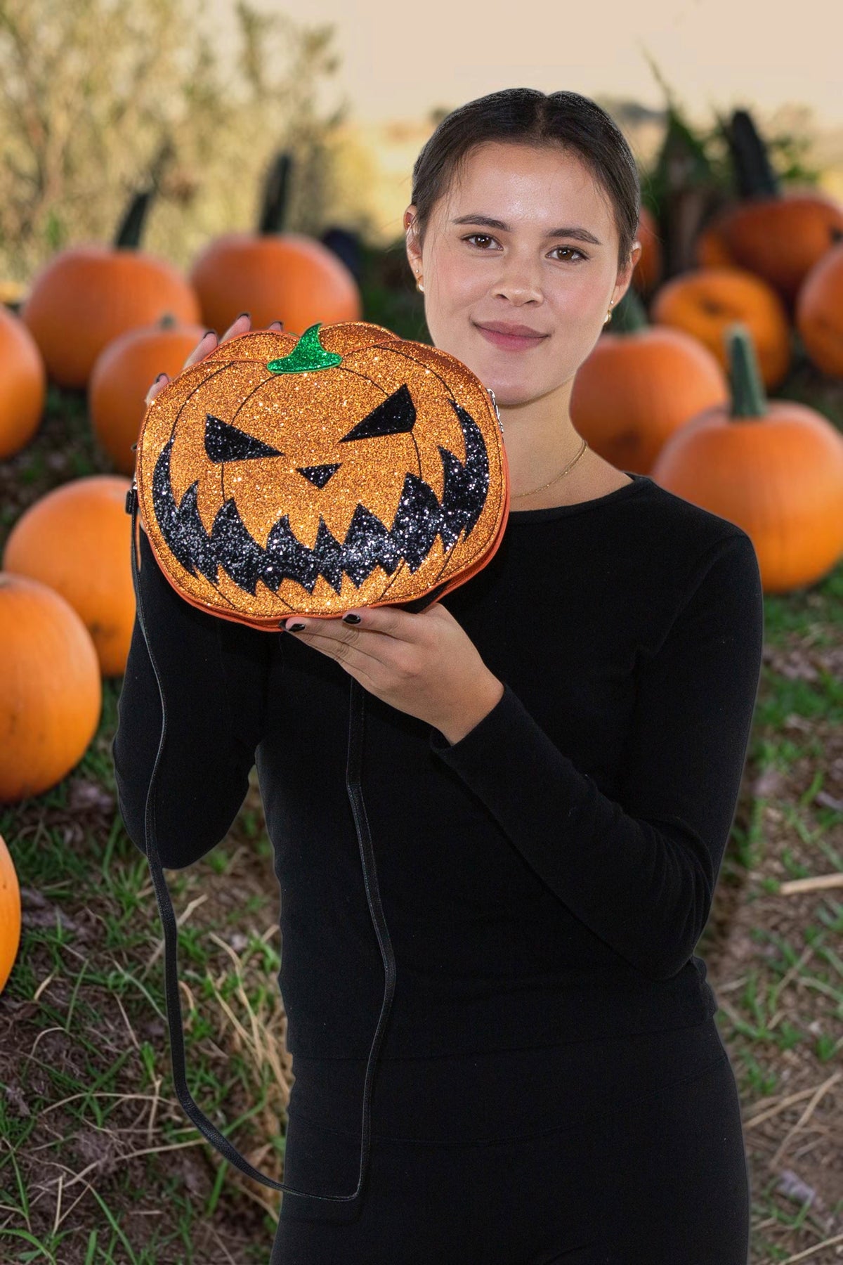 Halloween-Emporium glitter jack-o-lantern crossbody bag with orange vinyl and black smile in a pumpkin patch