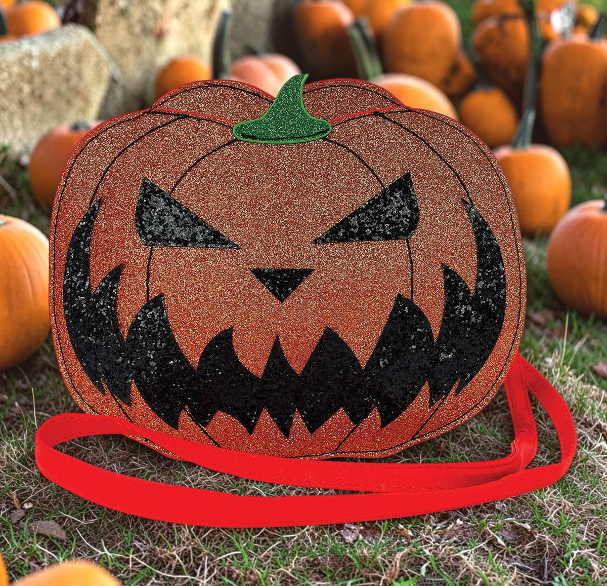 Halloween-Emporium glittery orange jack-o-lantern vinyl crossbody bag with a black jagged smile and orange strap.