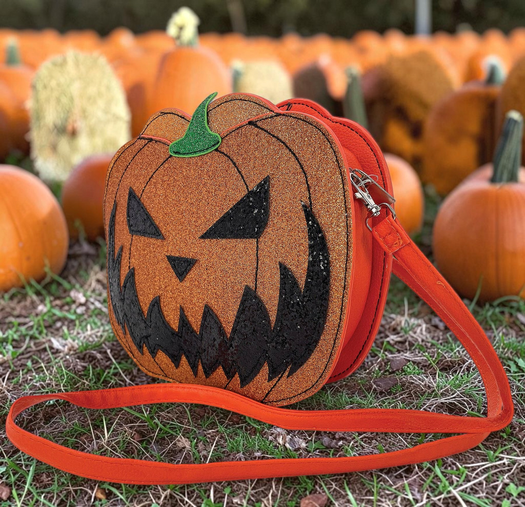 Halloween-Emporium glittery orange vinyl jack-o-lantern crossbody bag with an adjustable orange strap in a pumpkin patch