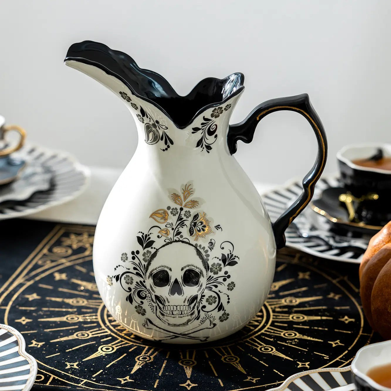 Halloween-Emporium gothic skull ceramic pitcher in white stoneware with black and gold floral detailing.