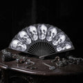 Halloween-Emporium gothic handheld folding fan featuring a monochromatic skull pattern on a black background.