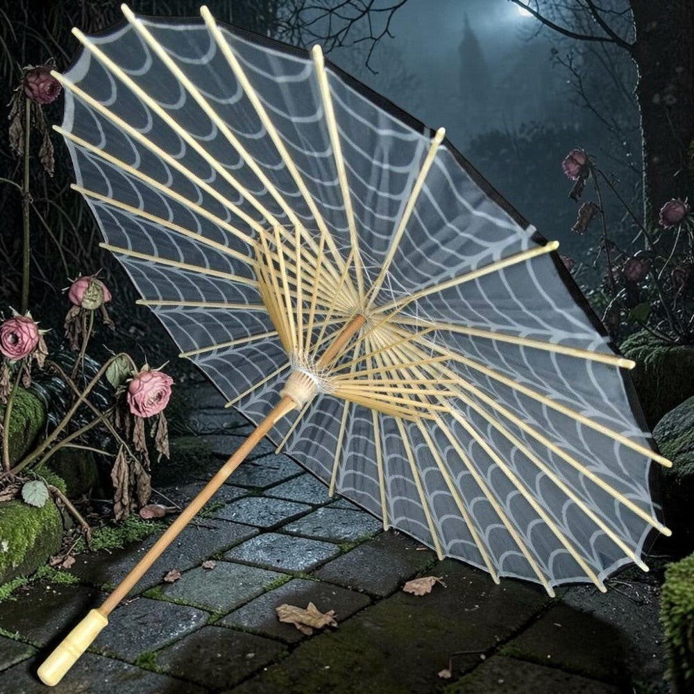 Halloween-Emporium gothic parasol with white spider web pattern on a bamboo frame in a dark garden setting.