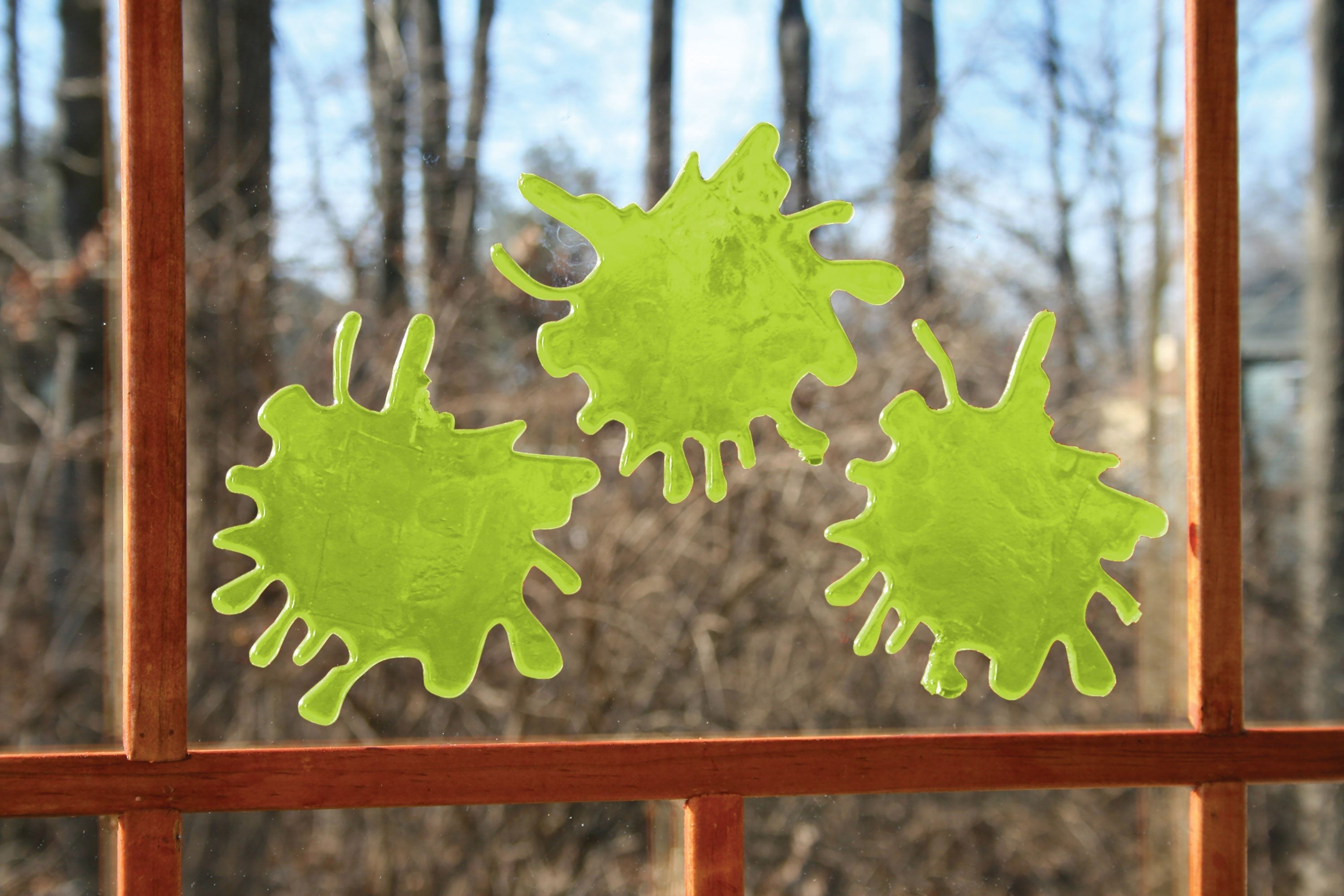 Halloween-Emporium glow-in-the-dark green zombie blood splatter window clings on a glass pane