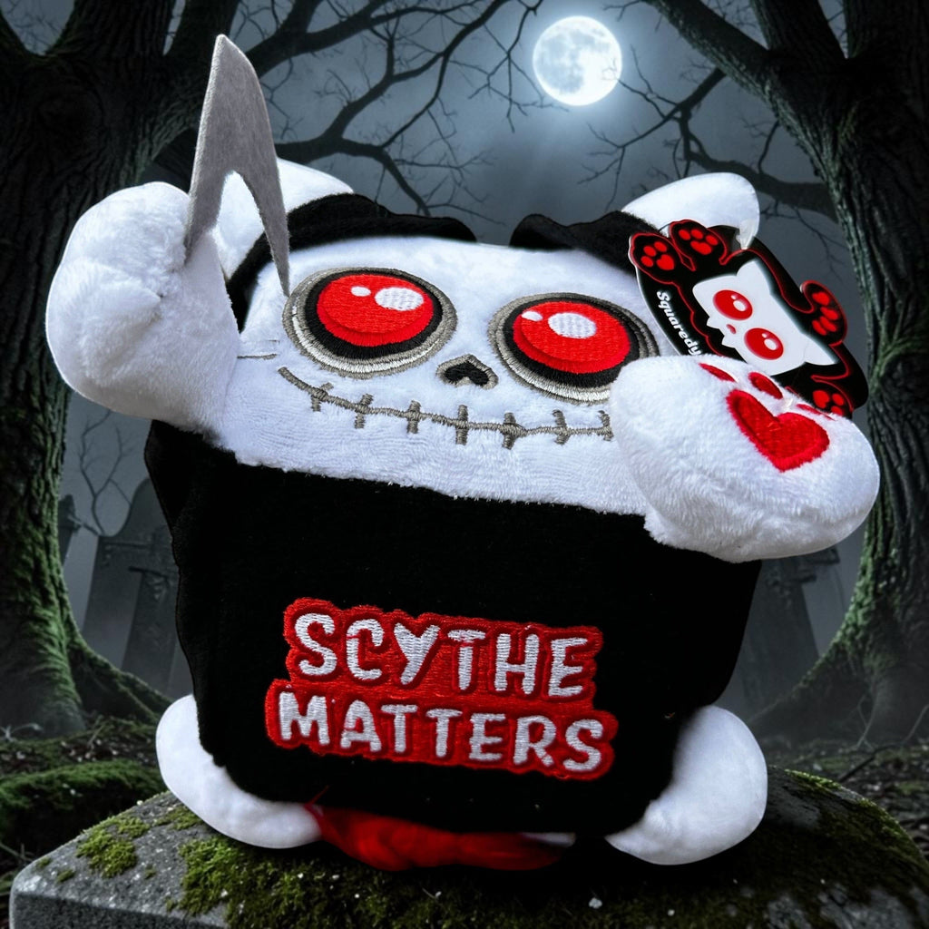 Halloween-Emporium Squaredy Cats Grim Reaper plush toy with red eyes, black hooded cloak, and scythe on a tombstone.