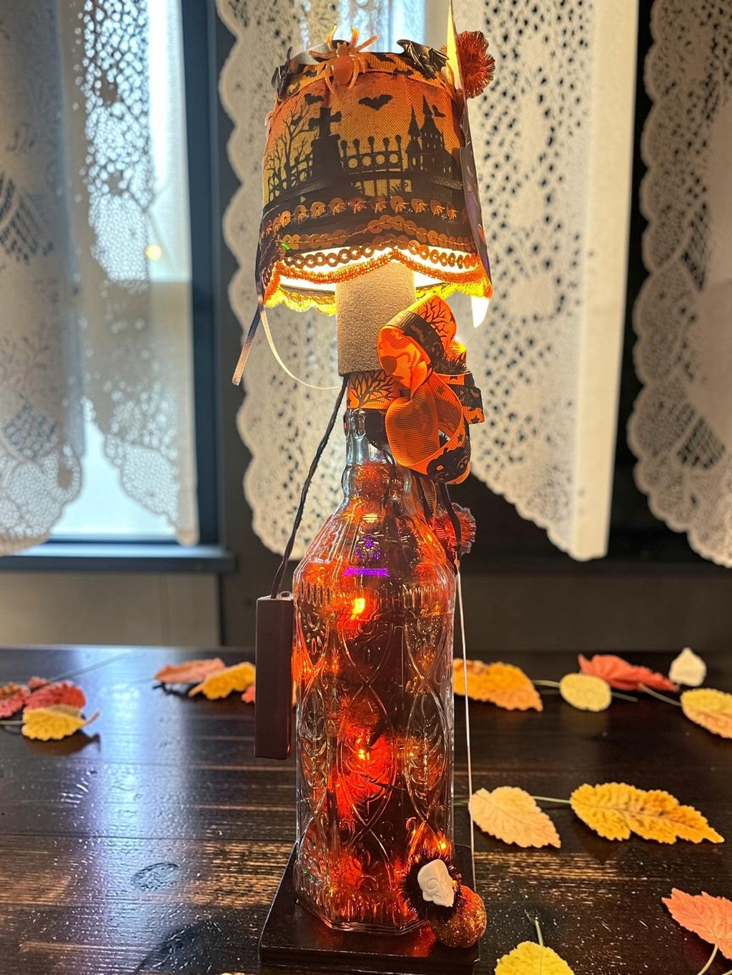 Halloween-Emporium Randy Hendrickson handcrafted LED bottle lamp with a spooky graveyard scene shade and orange lights.