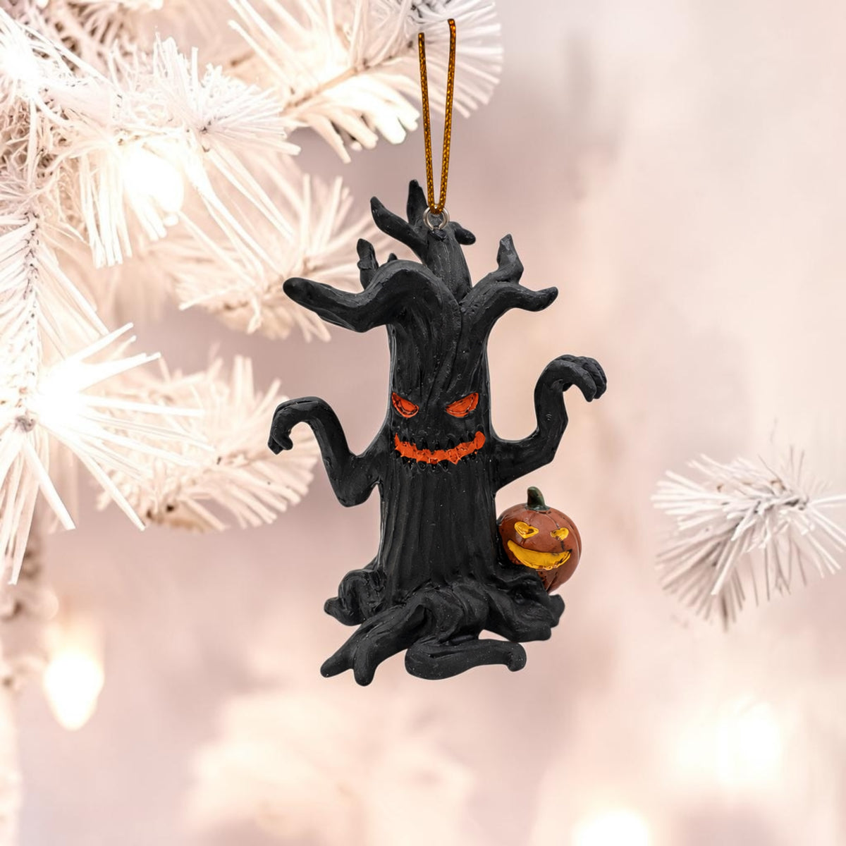 Halloween-Emporium black haunted tree ornament with glowing orange eyes and a jack-o-lantern hanging on a white tree.