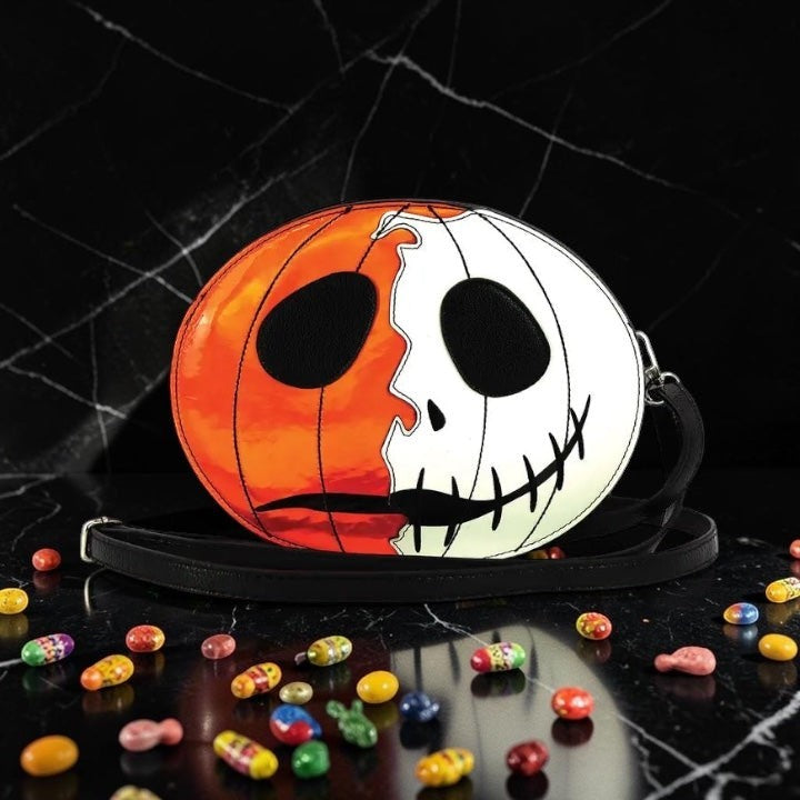 Halloween-Emporium jack-o-lantern crossbody bag with split orange and white pumpkin face design and shoulder strap.