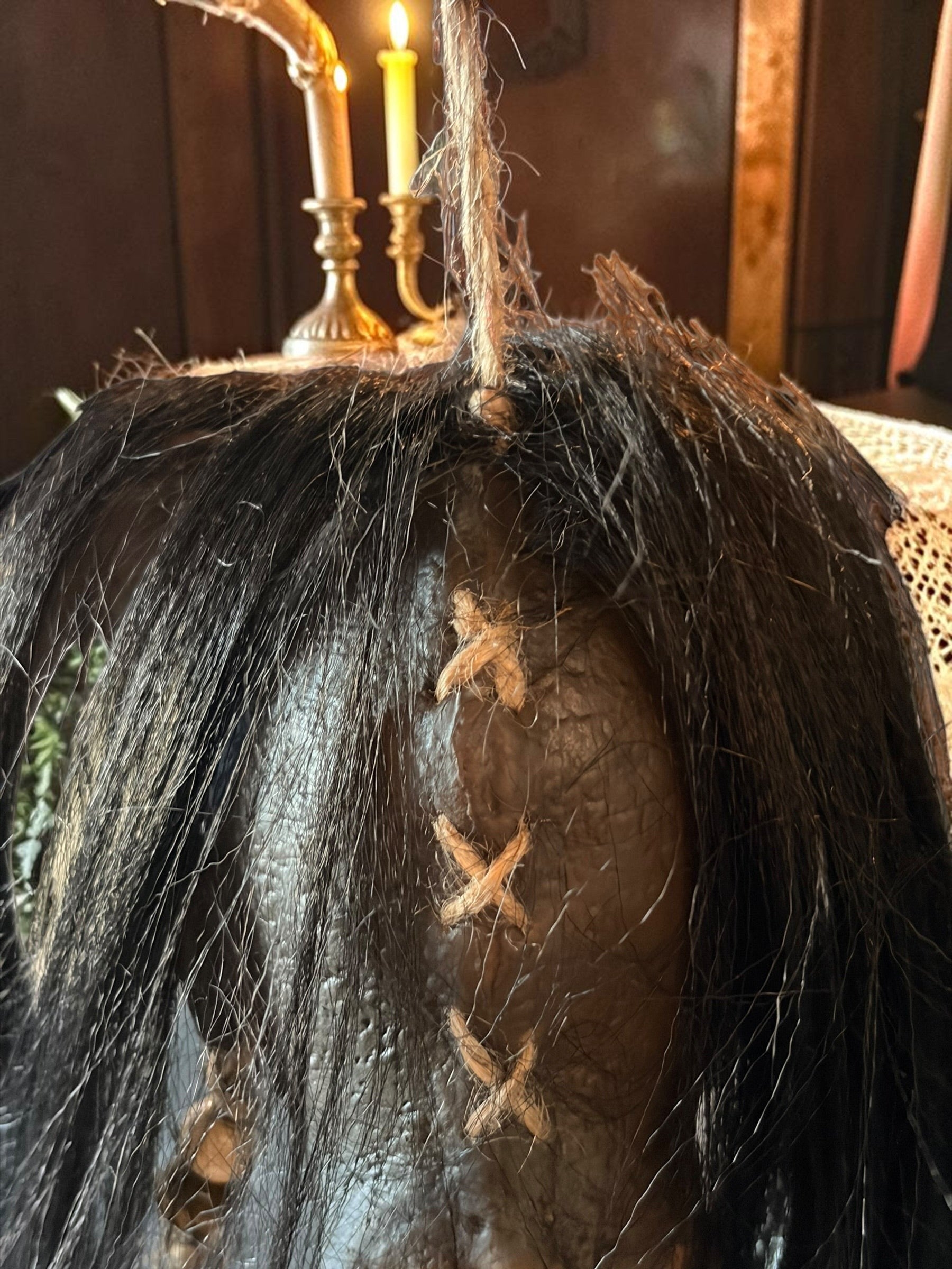 Halloween-Emporium latex voodoo shrunken head prop with black synthetic hair and rustic jute rope stitching detail.