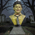Halloween-Emporium Leatherface mini bust featuring detailed mask and yellow apron in a spooky graveyard setting.