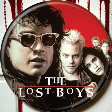 Halloween-Emporium The Lost Boys movie poster pinback button featuring the iconic vampire film cast on a red background