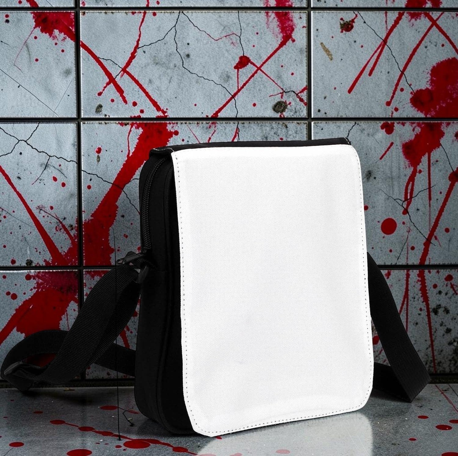 Halloween-Emporium messenger bag with a blank white flap and black polyester body against a blood-splattered wall.