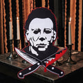 Halloween-Emporium 4-inch Michael Myers horror sticker featuring the iconic slasher mask and crossed bloodied knives.