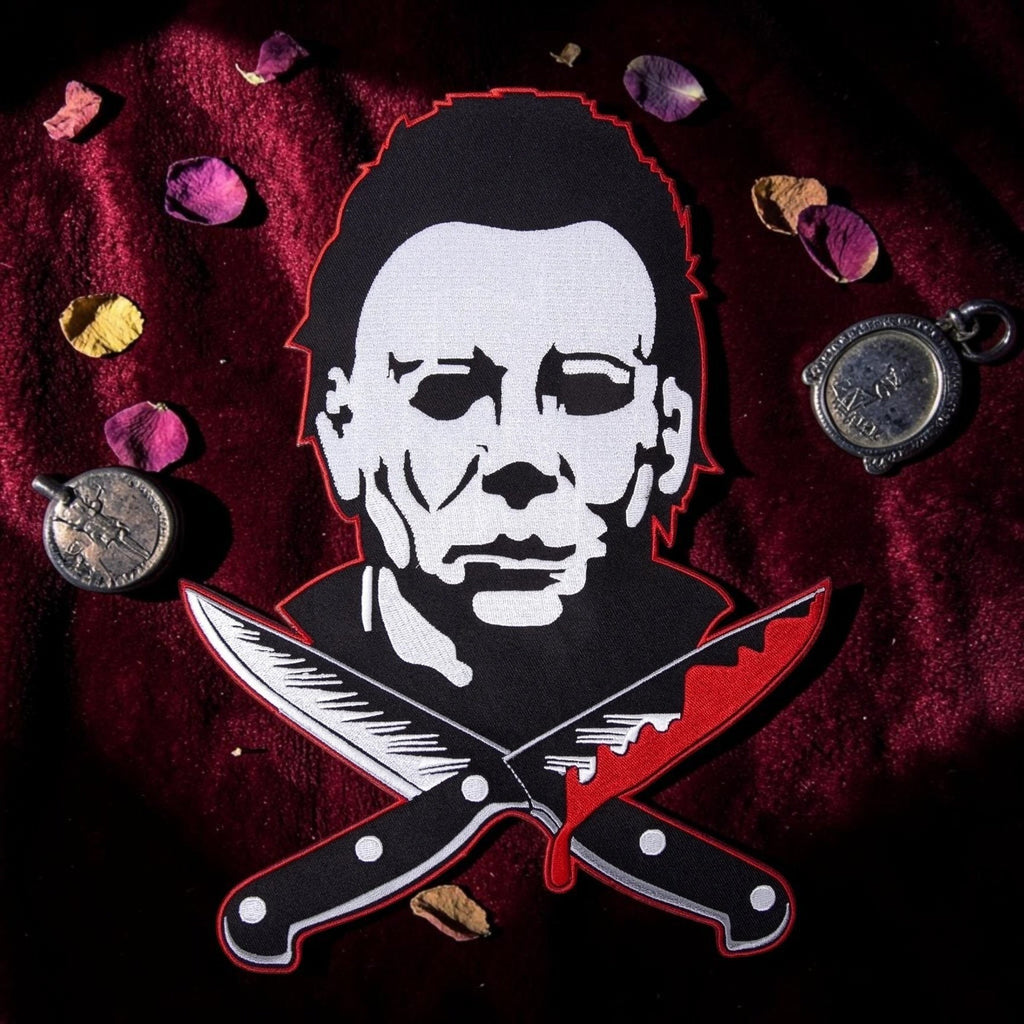 Halloween-Emporium large Michael Myers embroidered patch with crossed bloody knives on a dark red velvet background.