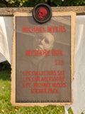 Halloween-Emporium Michael Myers mystery box promotional sign with red text on aged paper held by a skull wax seal.