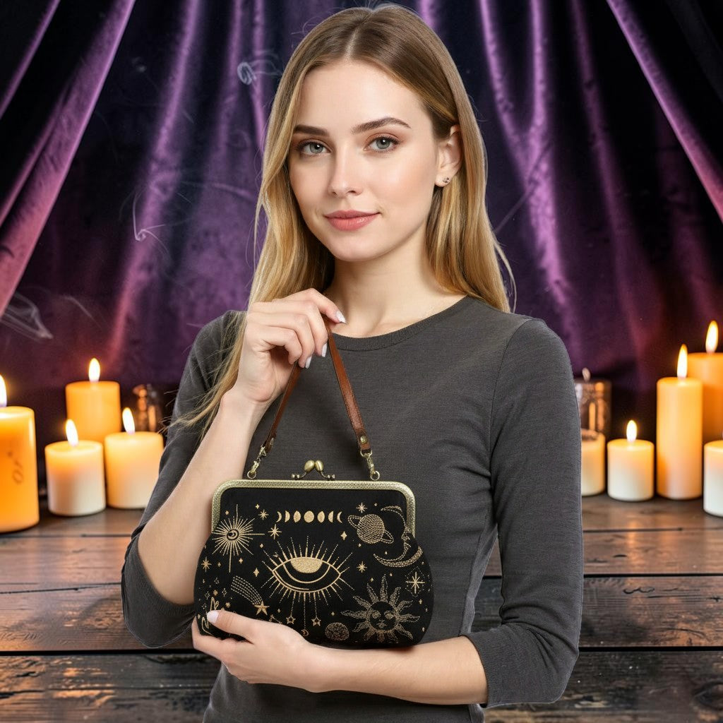Halloween-Emporium moon phase kisslock handbag with gold celestial embroidery held by a woman in a candlelit setting