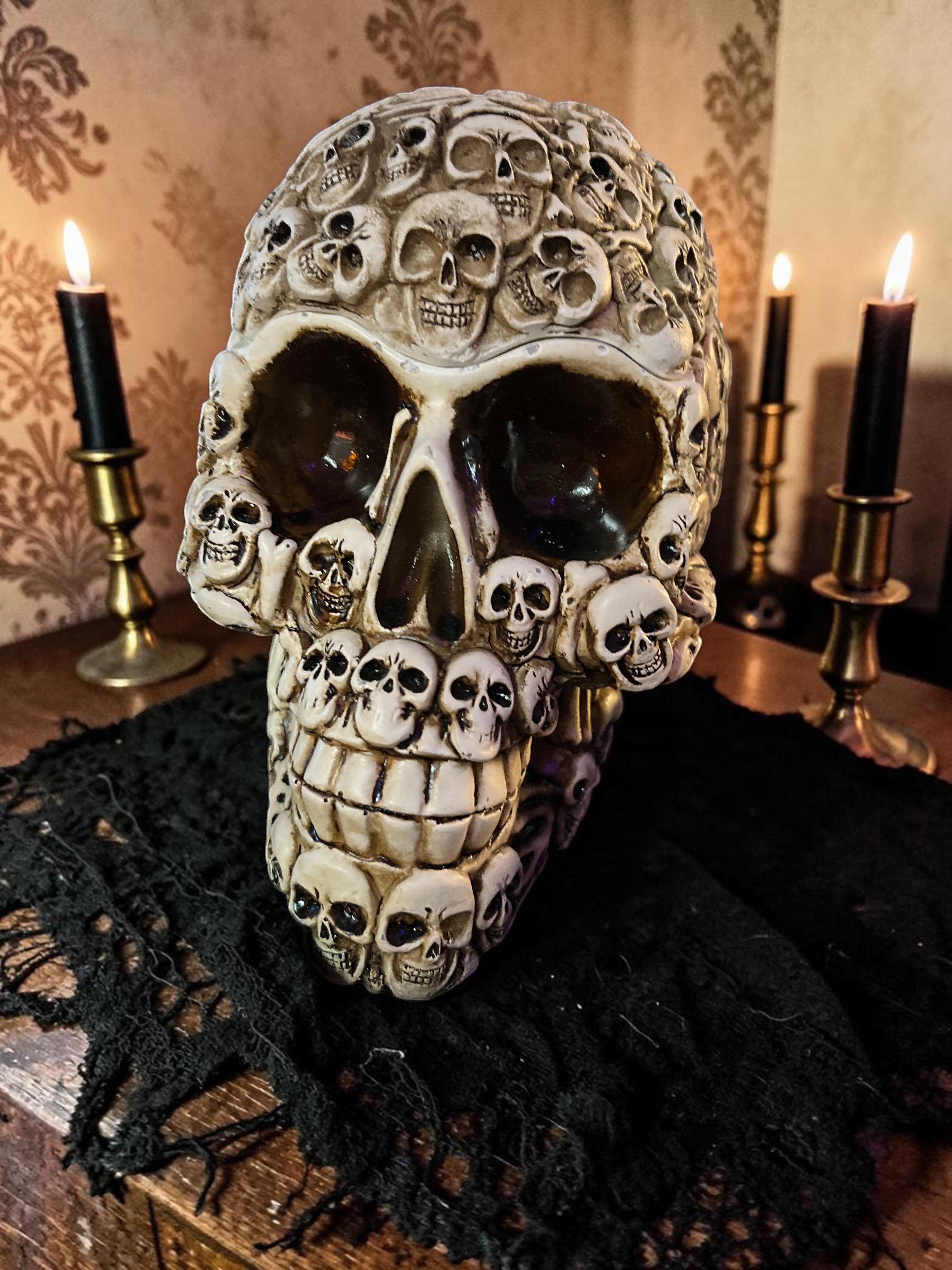 Halloween-Emporium decorative skull container with a mosaic of small skulls and an antique finish on a black cloth.