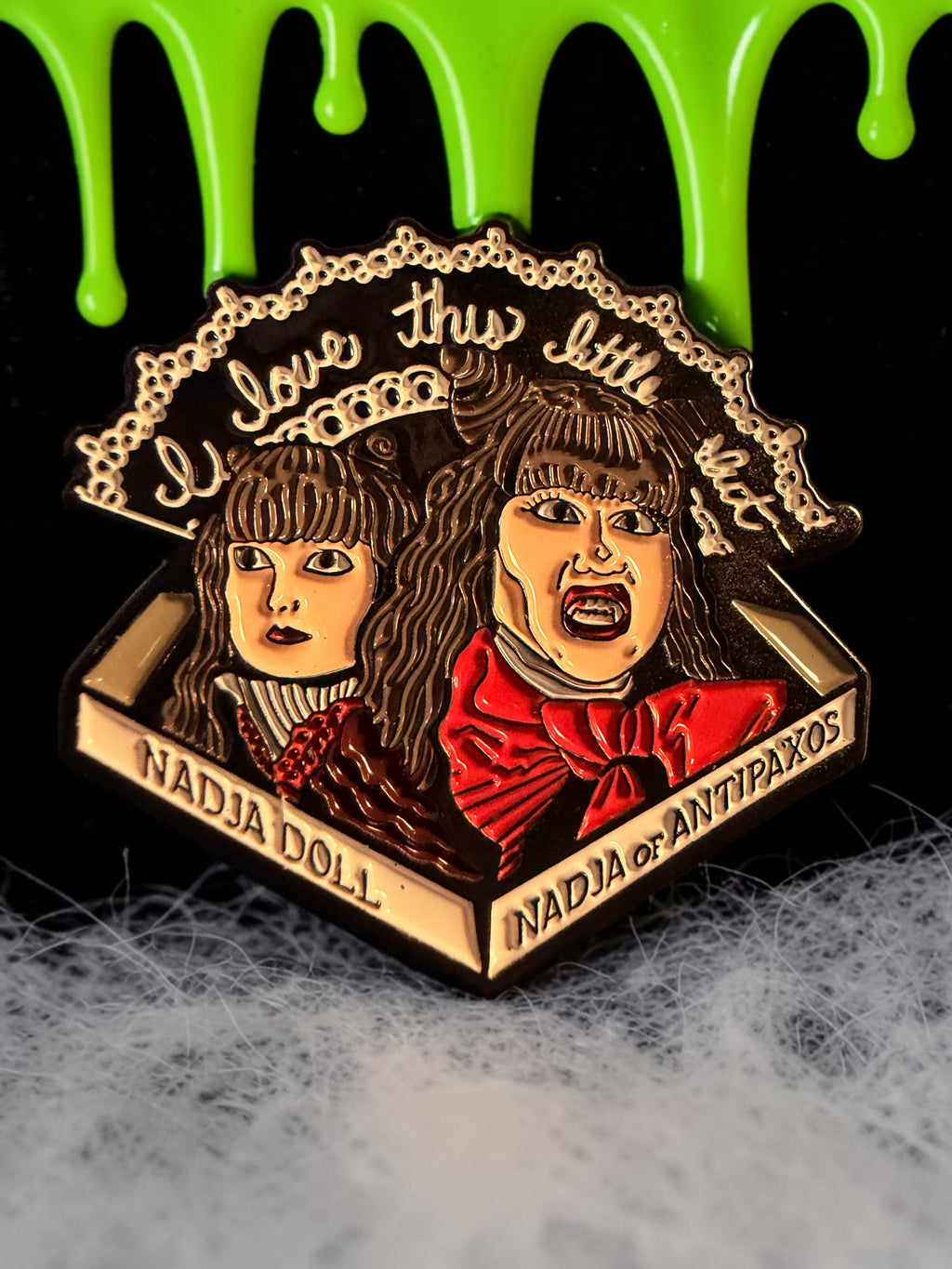 Halloween-Emporium enamel pin featuring Nadja and her doll from What We Do in the Shadows with gothic text detail.