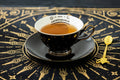 Halloween-Emporium porcelain tea cup and saucer set featuring a black exterior with gold constellations and Ouija board