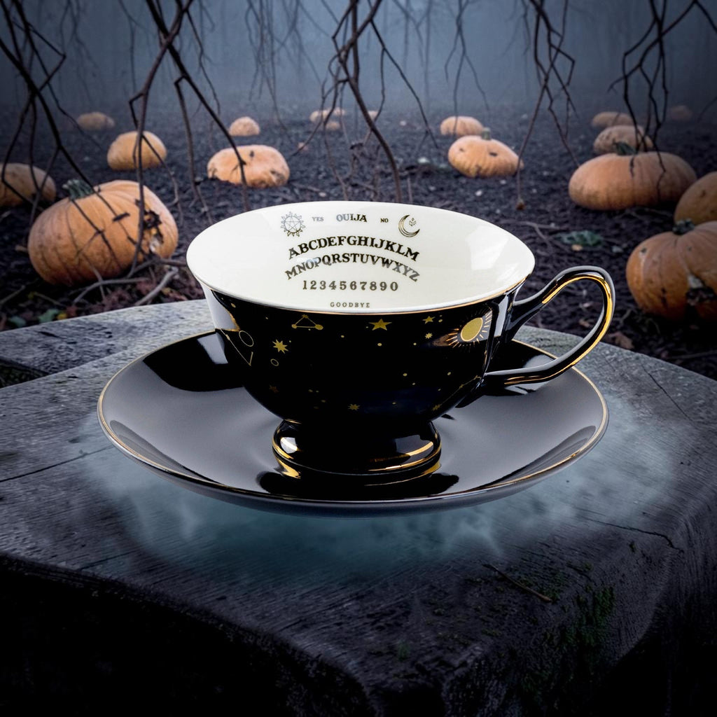 Halloween-Emporium porcelain tea cup and saucer set featuring a black exterior with gold constellations and Ouija board