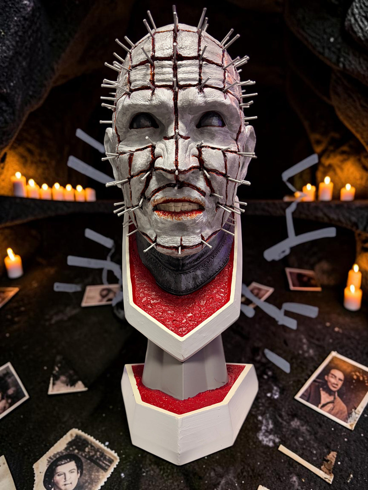 Halloween-Emporium hand painted Pinhead bust with realistic blood effects and textured base in a dark horror setting.