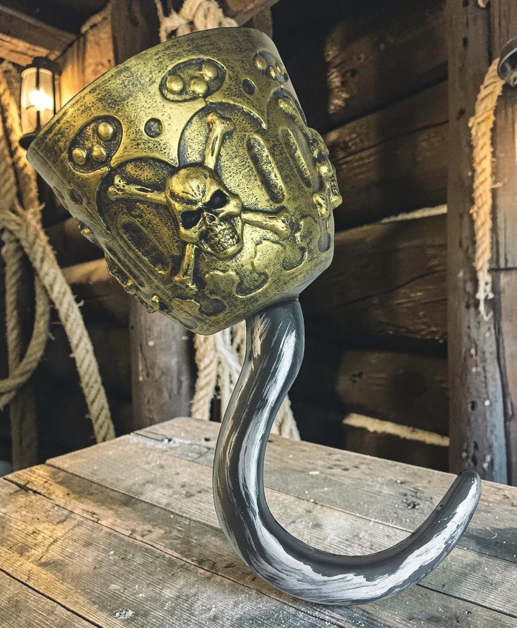 Halloween-Emporium pirate captain hook with a weathered metallic finish and an antique-gold skull and crossbones base.
