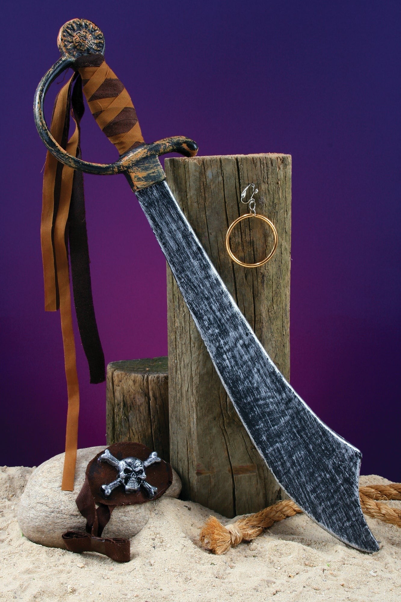 Halloween-Emporium deluxe pirate sword set with metallic cutlass, gold hoop earring, and skull patch on sandy base.