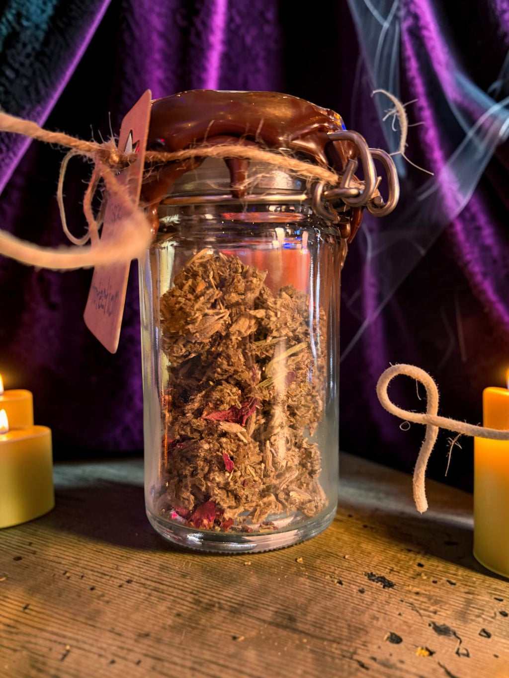 Halloween-Emporium Prosperity and Protection incense blend in a wax-sealed glass jar with herbs and flower petals.