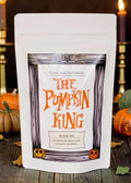 Halloween-Emporium The Pumpkin King black tea pouch with pumpkin pie spices and orange sprinkles on a rustic table.
