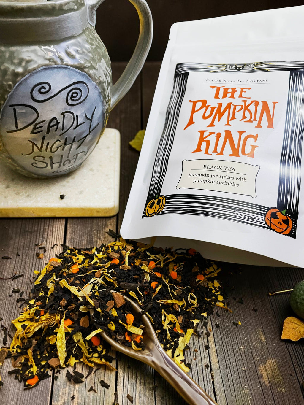 Halloween-Emporium Pumpkin King black tea blend with cinnamon, cloves, and orange pumpkin sprinkles on a wooden table.