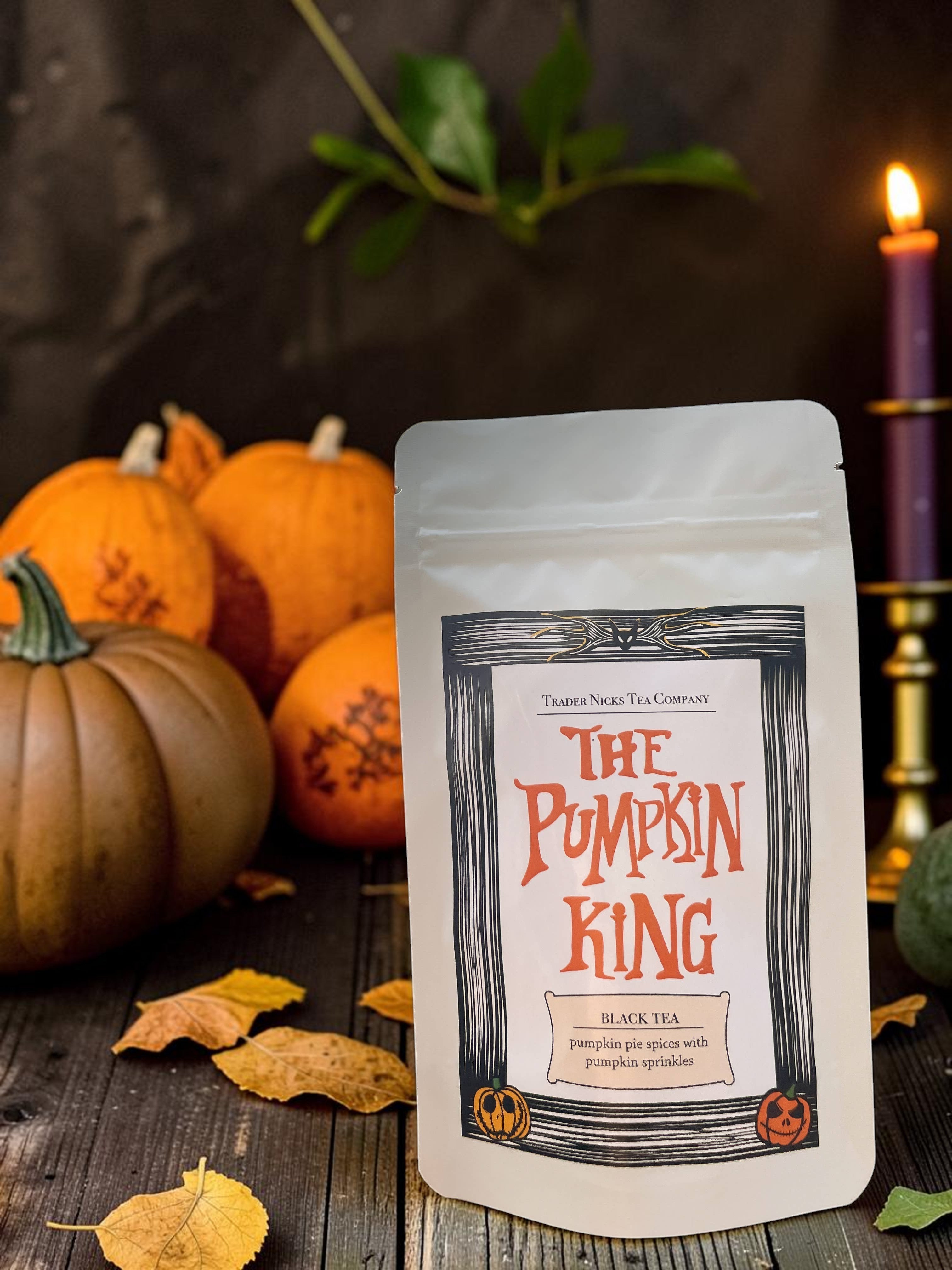 Halloween-Emporium Pumpkin King black tea pouch with pumpkin pie spices, set against a backdrop of pumpkins and a candle.