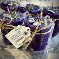Halloween-Emporium purple soy-dipped divination votive candles topped with ritual herbs and twine-tied tags