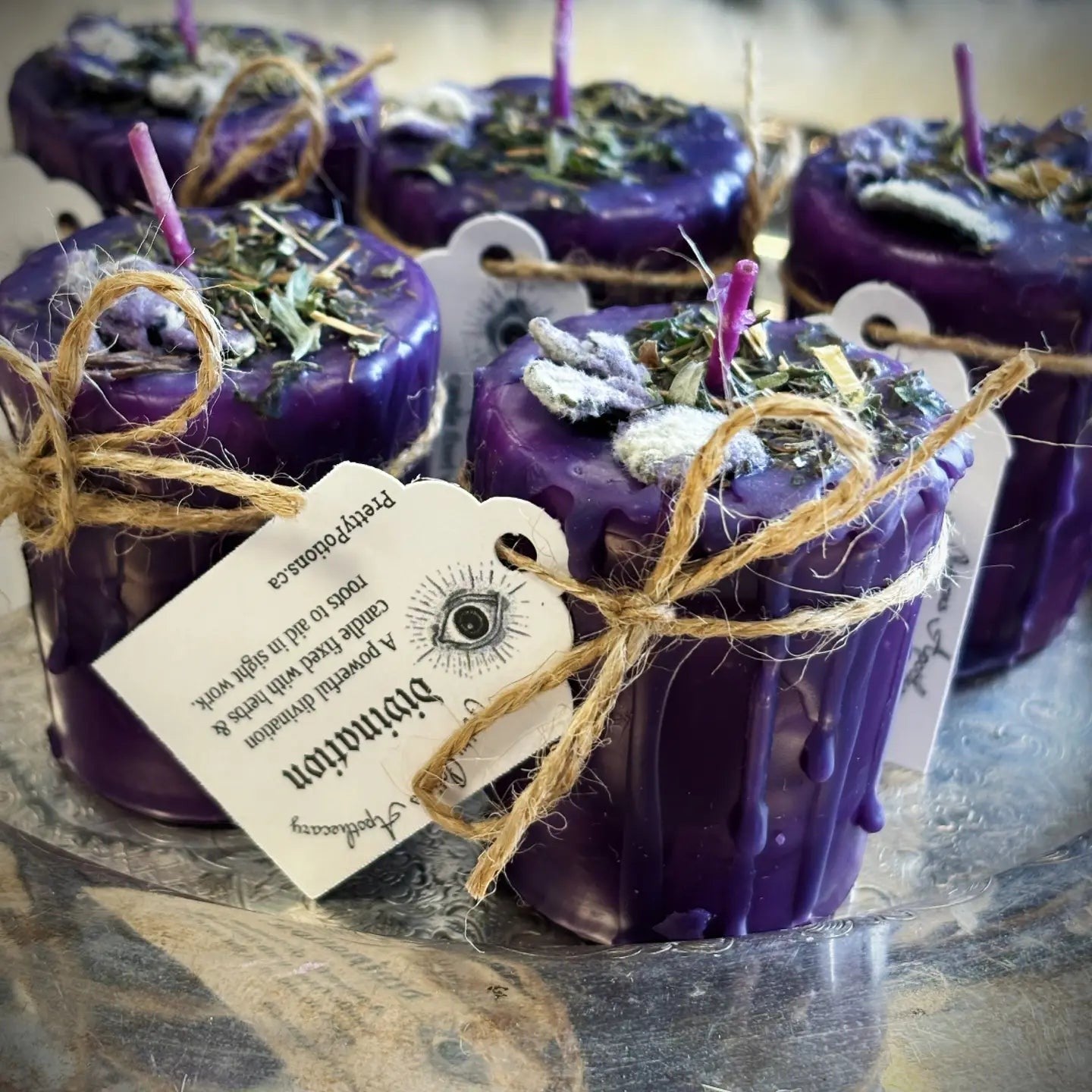 Halloween-Emporium purple soy-dipped divination votive candles topped with ritual herbs and twine-tied tags