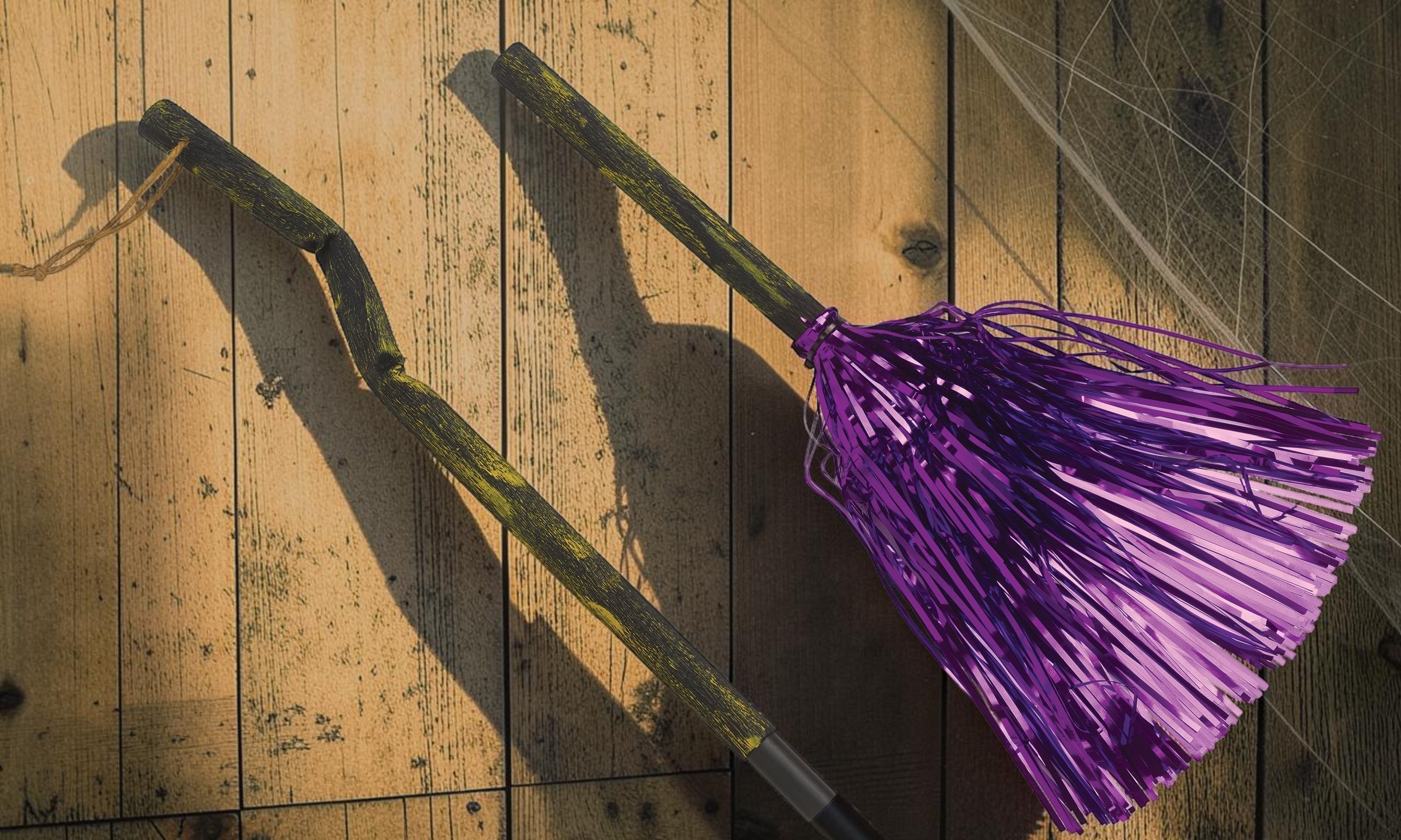 Halloween-Emporium hanging witch broomstick prop with a rustic gnarled handle and shimmering purple tinsel bristles.