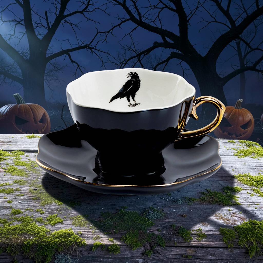 Halloween-Emporium porcelain tea cup and saucer set in glossy black with gold trim and a raven motif inside.