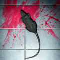 Halloween-Emporium realistic black rat prop with a long tail placed on a tiled floor with a red blood splatter effect.
