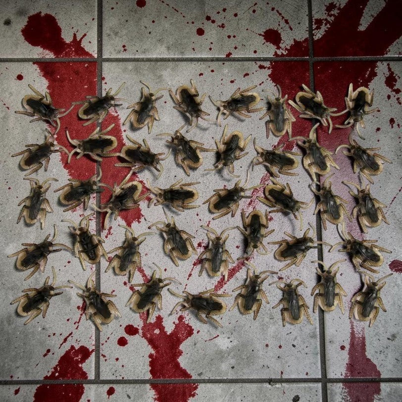 Halloween-Emporium realistic brown plastic cockroach props scattered on a blood-splattered tiled floor