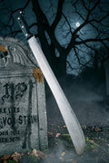Halloween-Emporium 27-inch realistic machete costume prop with weathered metallic blade leaning on a stone tombstone.