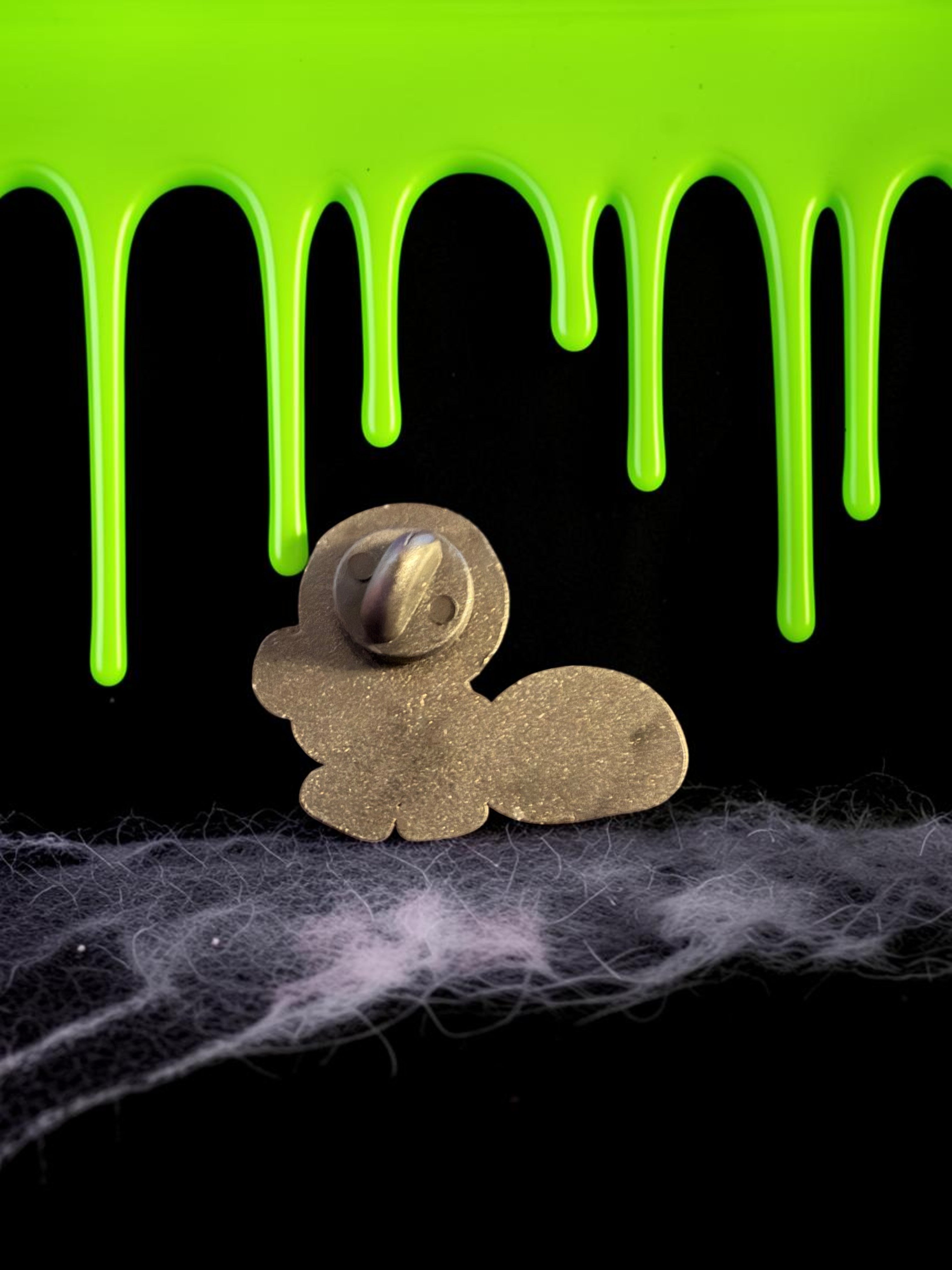 Halloween-Emporium Trick 'r' Treat Sam enamel pin back view showing metal pin post against green slime background