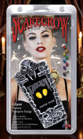 Halloween-Emporium Scarecrow Glam Deluxe gold vampire fangs in blister packaging featuring a model wearing the fangs.