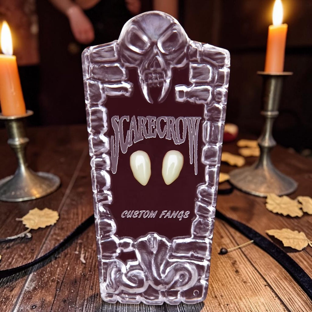 Halloween-Emporium Scarecrow Small Deluxe Fangs in a decorative tombstone-shaped case on a wooden table with candles.