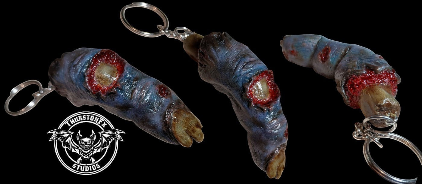 Halloween-Emporium ThurstonFX Studios severed finger keychain with realistic decaying skin and bloody bone detail.