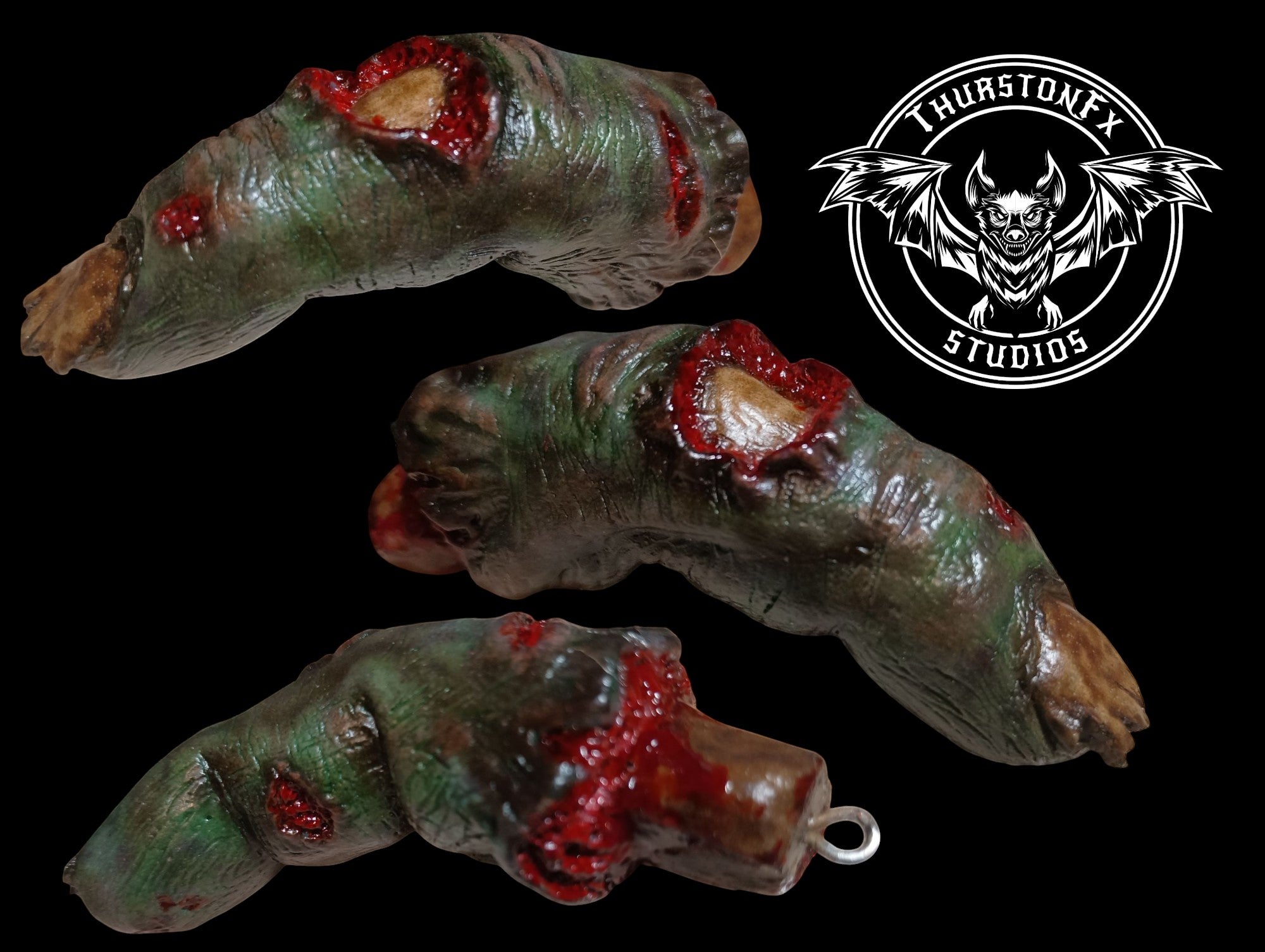 Halloween-Emporium THURSTONFX STUDIOS severed green zombie finger keychain with realistic decaying skin and bloody wounds.