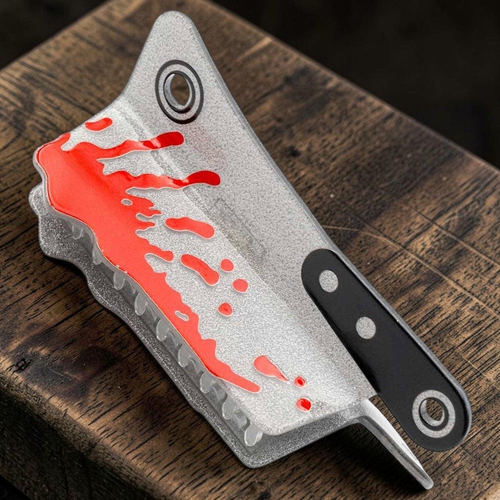 Halloween-Emporium silver glitter cleaver claw clip with red blood splatter detail on a wooden surface.