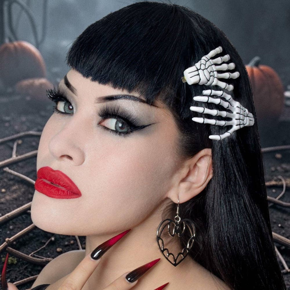 Halloween-Emporium white skeleton bone hand hairslides worn by a woman with dark hair and bold makeup