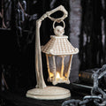 Halloween-Emporium bone-white skeleton hand lantern with a skull finial and LED light for gothic tabletop decor.